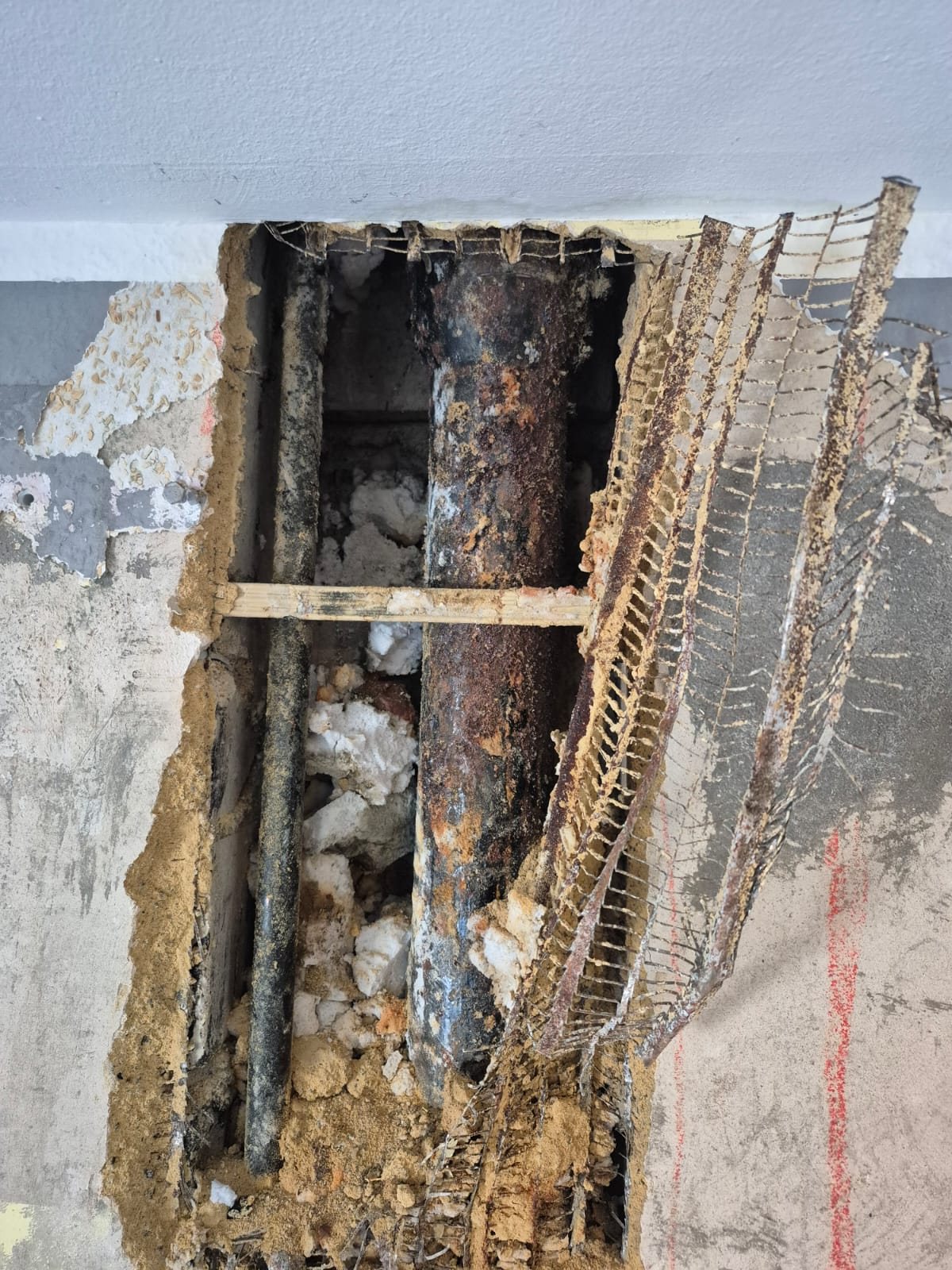 Detailaufnahme eines korrodierten Rohrs im geöffneten Wandbereich